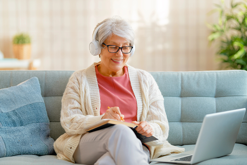 Joyful beautiful senior woman is using laptop sitting