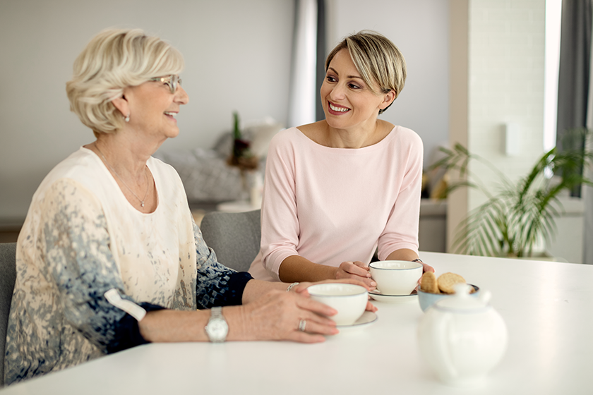 happy-woman-her-senior-mother-talking-while-drinking-coffee